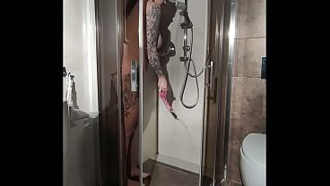 Busty woman takes a shower and masturbates with a dildo.
