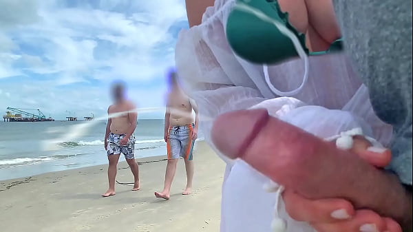Busty milf takes stranger’s cock out of pants right on the beach